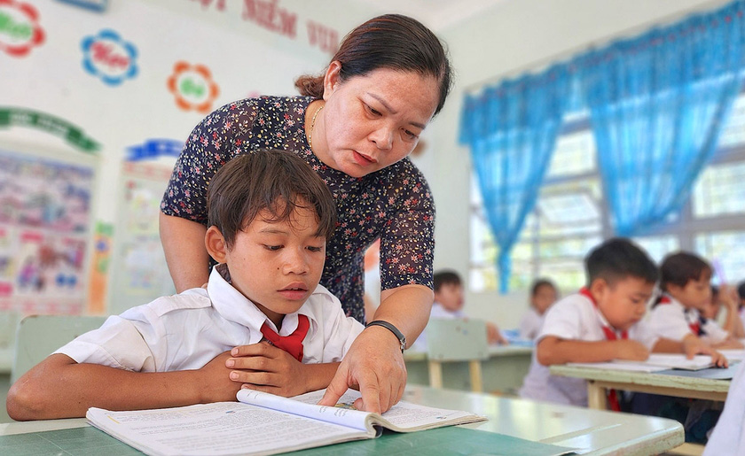 Cô Phan Thị Khánh luyện đọc, viết kỹ càng cho em Rơ Châm Ngoan - Ảnh: NHÃ TRẦN